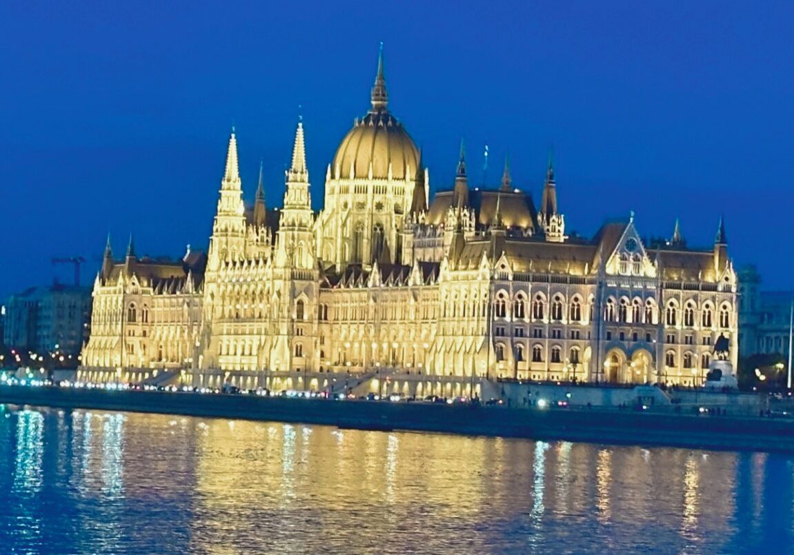 Hungarian Parliament illuminated along the Danube at dusk representing European cultural travel.